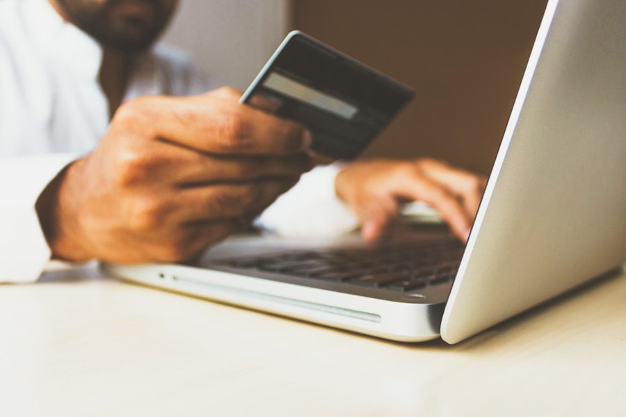 Person holding a credit card while shopping online on a laptop
